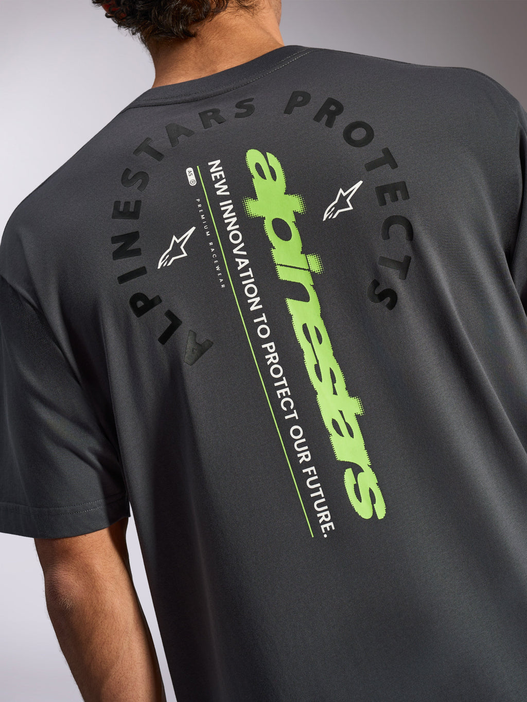 Alpinestars Overhang Oversized CSF Tee, maglietta a maniche corte, grigio antracite, vista posteriore con un grande logo verticale verde lime e grafica nera Alpinestars Protects, abbigliamento sportivo casual ispirato al motorsport