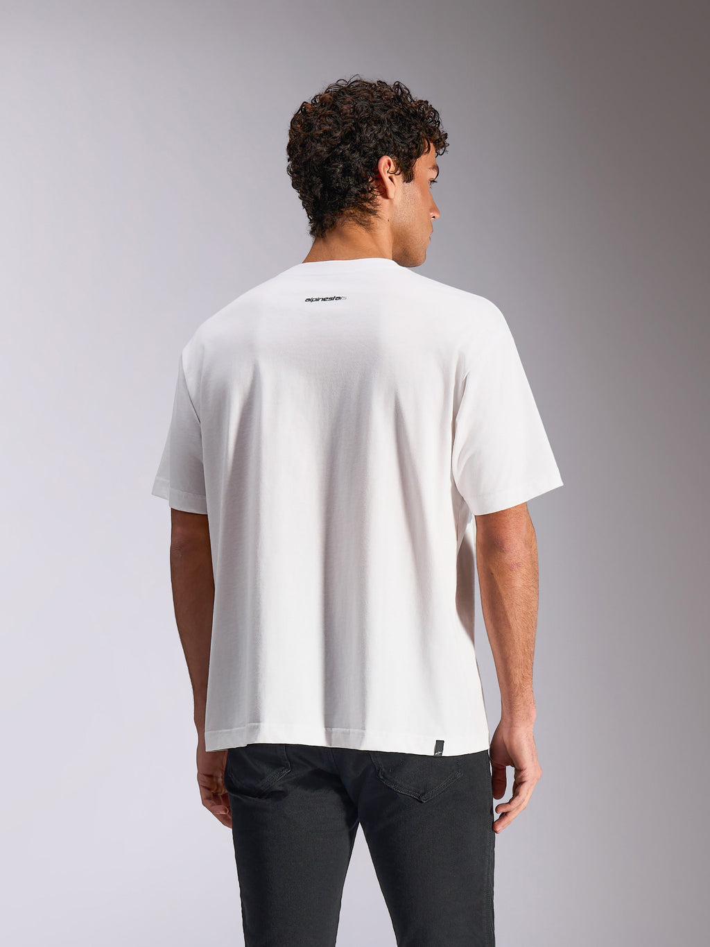 Alpinestars Focused Oversized CSF Tee, t-shirt a maniche corte, bianco, vista posteriore su modello con piccolo logo Alpinestars nero sotto la scollatura, vestibilità ampia oversize, streetwear casual