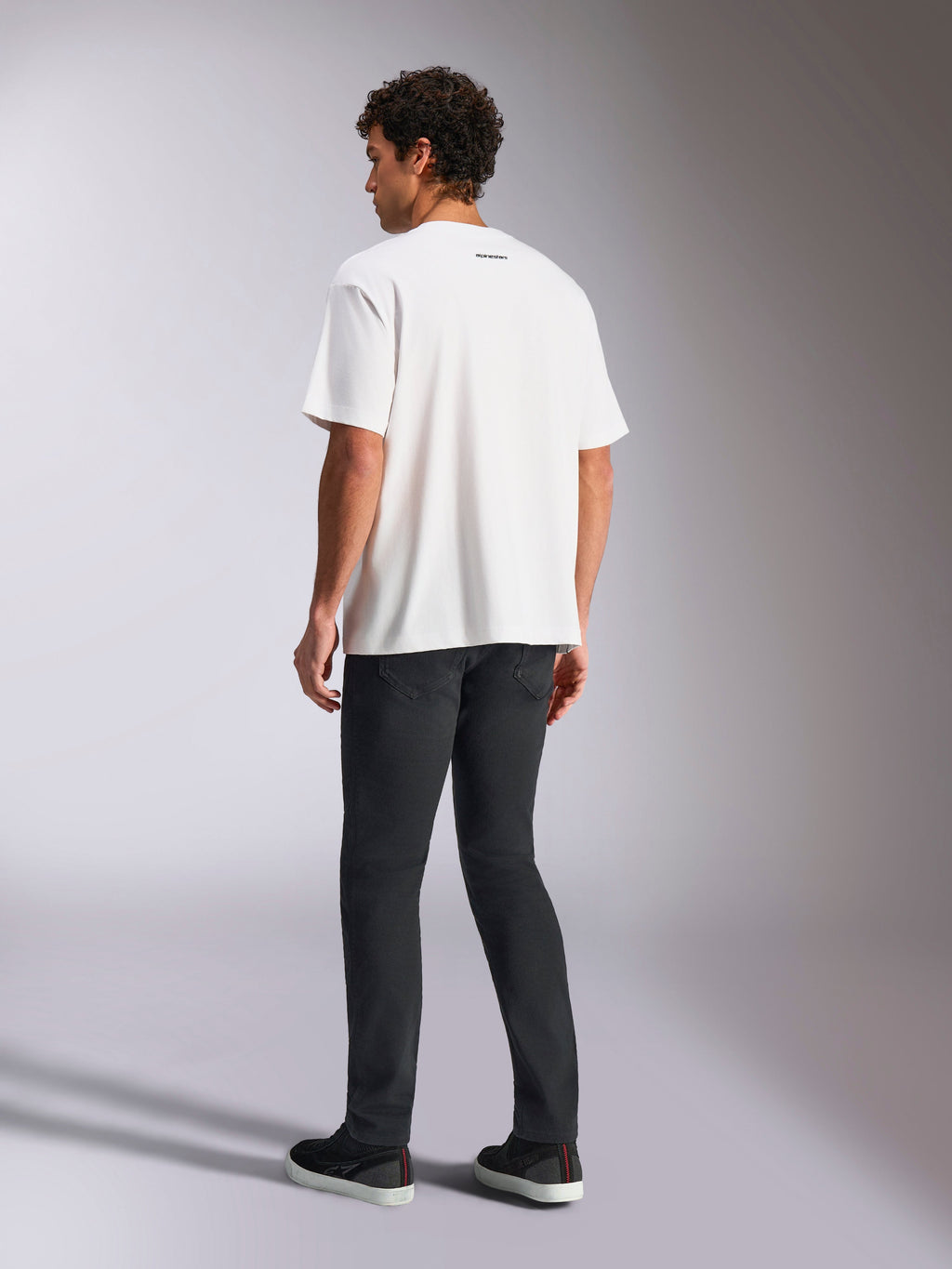 Alpinestars Focused Oversized CSF Tee, t-shirt a maniche corte, bianca, piccolo logo Alpinestars nero sul retro del collo, indossata con pantaloni neri, vestibilità oversize, streetwear casual ispirato al motorsport