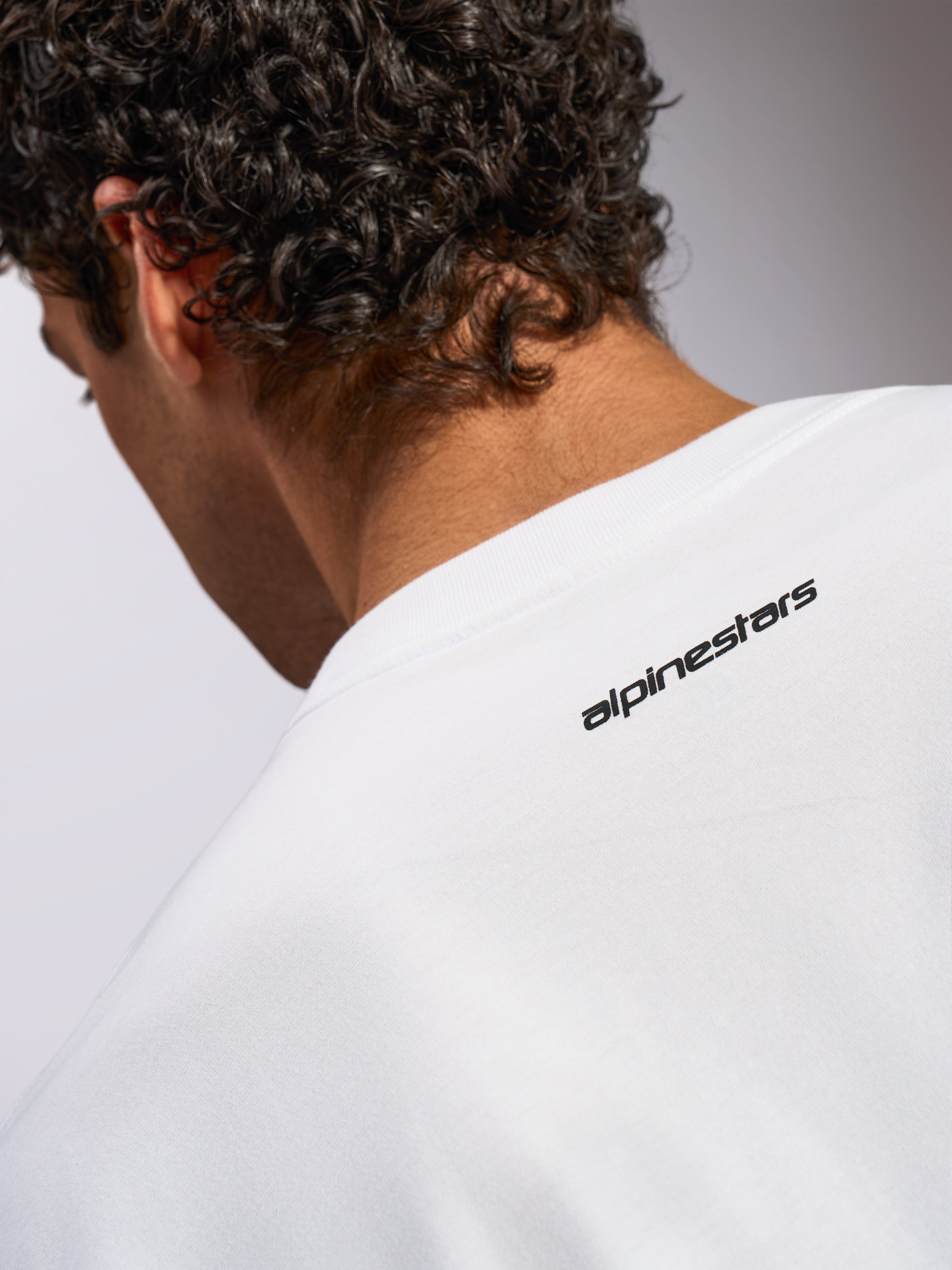 Alpinestars Focused Oversized CSF Tee, t-shirt a maniche corte, bianca, primo piano della parte posteriore del collo con piccolo logo Alpinestars nero, design casual d'ispirazione motorsport