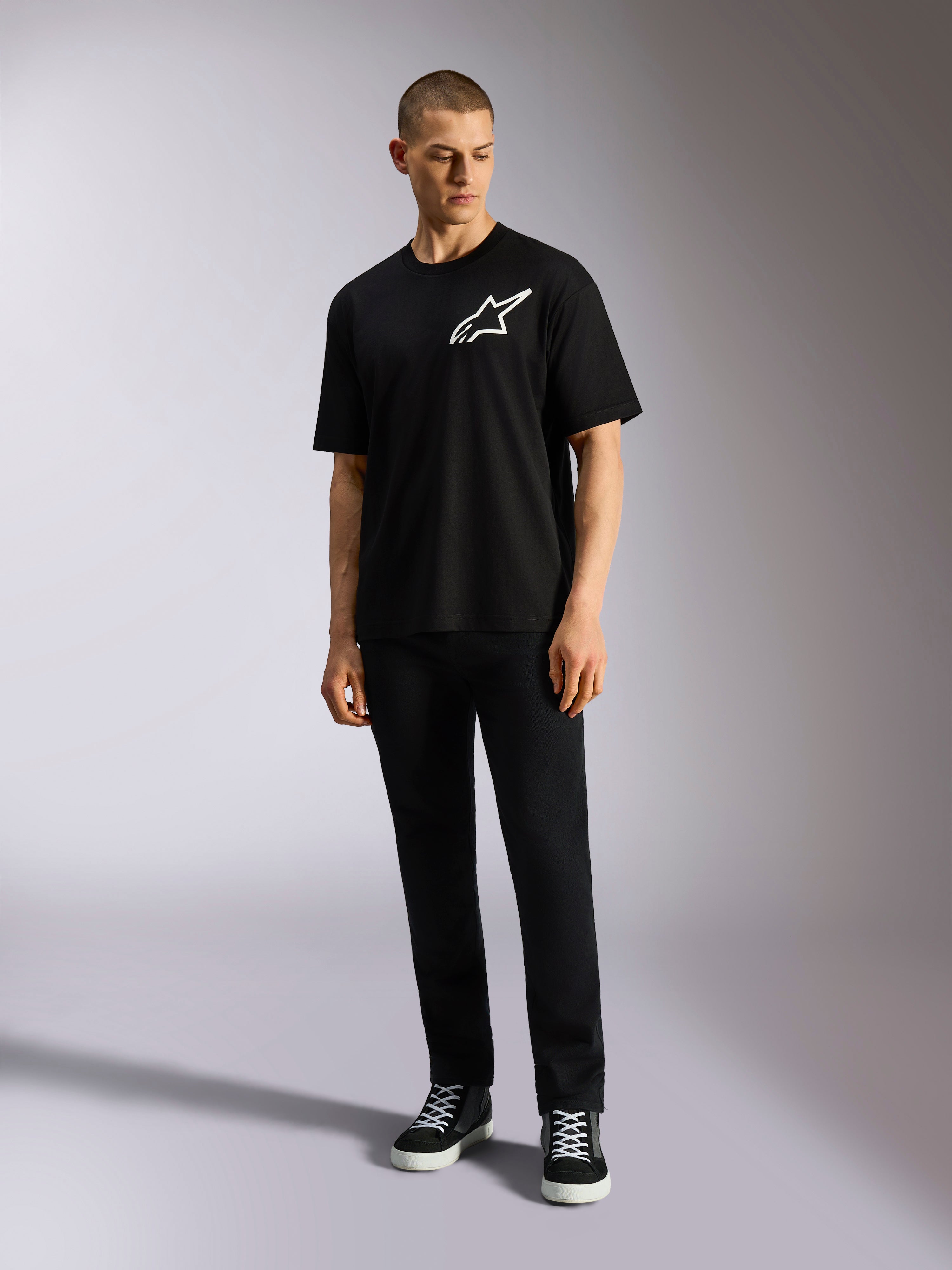 Alpinestars One Oversized CSF Tee, t-shirt a maniche corte, nero, logo Astars bianco sul petto, vestibilità oversize, indossata da un modello con pantaloni neri e sneakers, abbigliamento streetwear casual