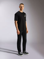 Alpinestars One Oversized CSF Tee, T-shirt a maniche corte, nera, logo Astars bianco sul petto, vestibilità oversize, indossata da un modello uomo con pantaloni neri e sneakers, streetwear casual ispirato al motorsport