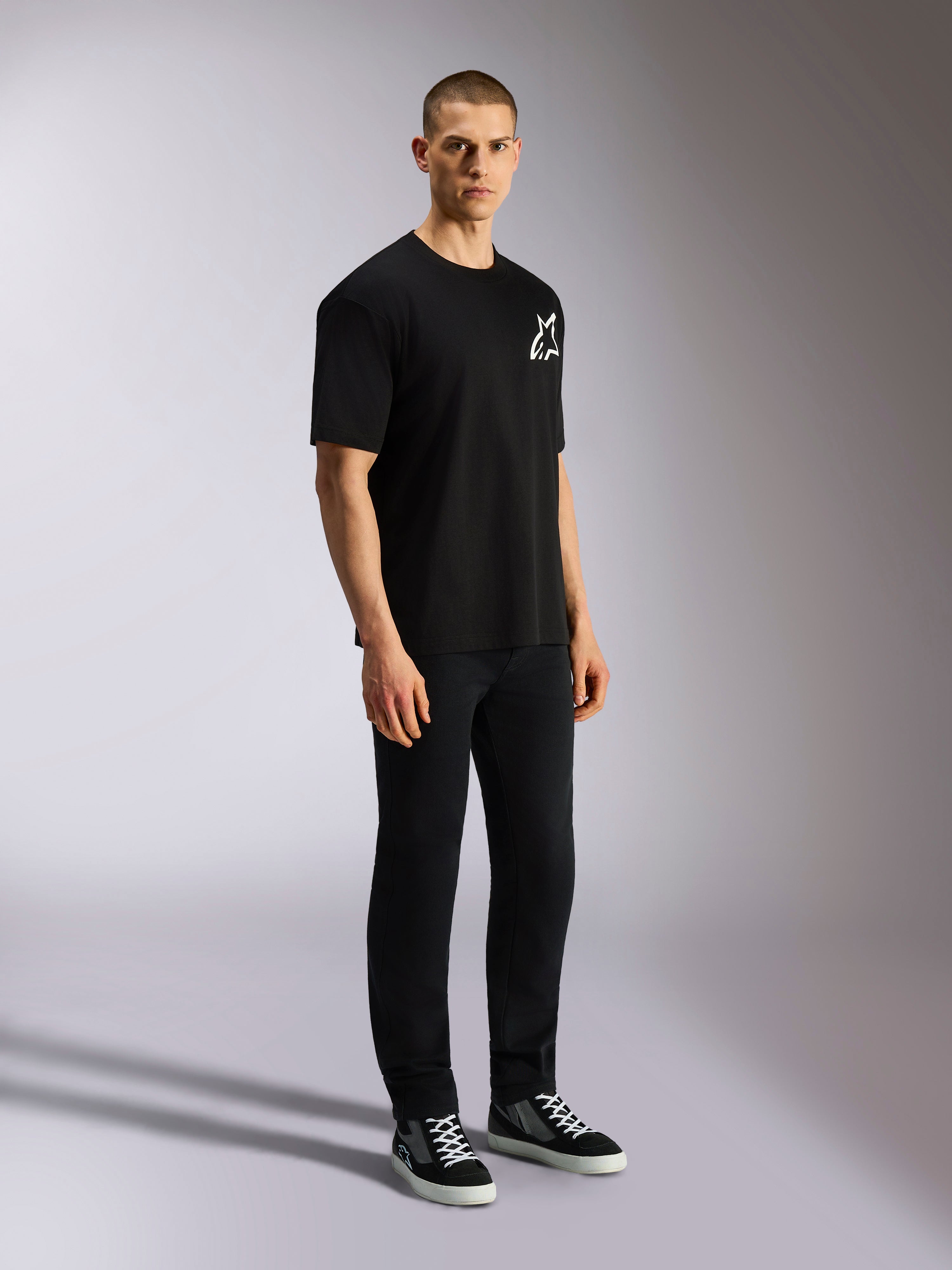 Alpinestars One Oversized CSF Tee, T-shirt a maniche corte, nera, logo Astars bianco sul petto, vestibilità oversize, indossata da un modello uomo con pantaloni neri e sneakers, streetwear casual ispirato al motorsport