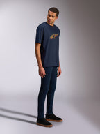 Alpinestars Alter Oversized CSF Tee, t-shirt a maniche corte, blu navy, logo Astars giallo e arancione, indossata da un modello con jeans scuri e sneakers nere, streetwear casual ispirato al motorsport