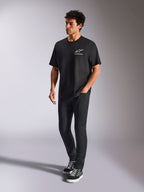 Alpinestars Wild Oversized CSF Tee, t-shirt a maniche corte, nero, logo Astars multicolore sul petto, stile casual streetwear indossata da un modello con pantaloni neri e sneakers alte