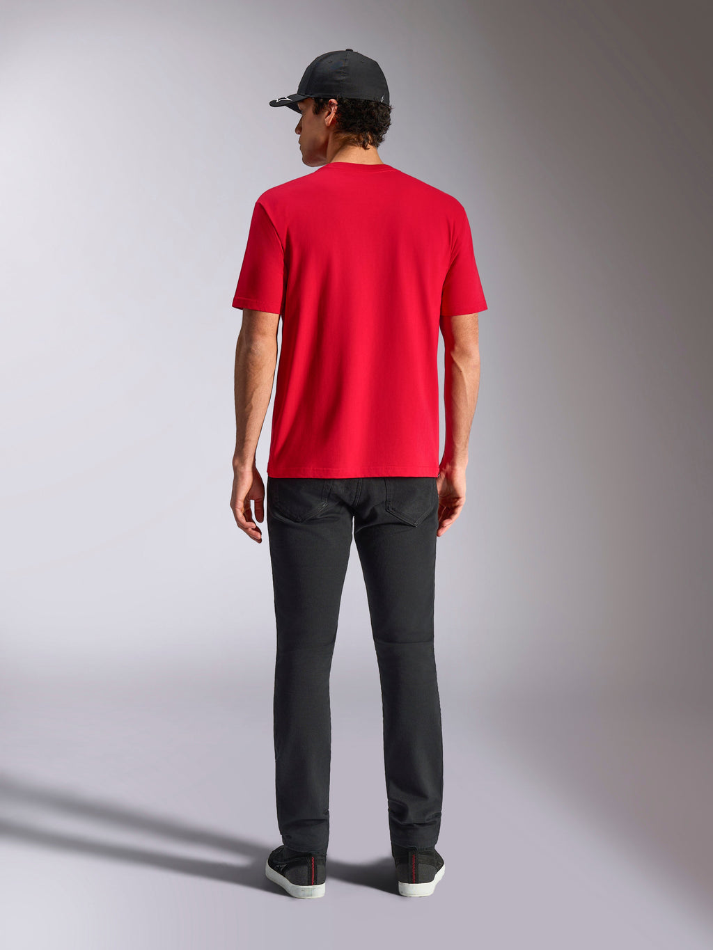 Alpinestars Noka CSF Tee, t-shirt a maniche corte, rossa, vista posteriore, abbinata a pantaloni neri e un cappellino da baseball nero, streetwear casual ispirato al motorsport