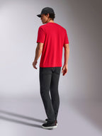 Alpinestars Noka CSF Tee, T-shirt a maniche corte, rosso, vista posteriore, abbinata a pantaloni neri e un cappellino da baseball nero, streetwear casual ispirato al motorsport