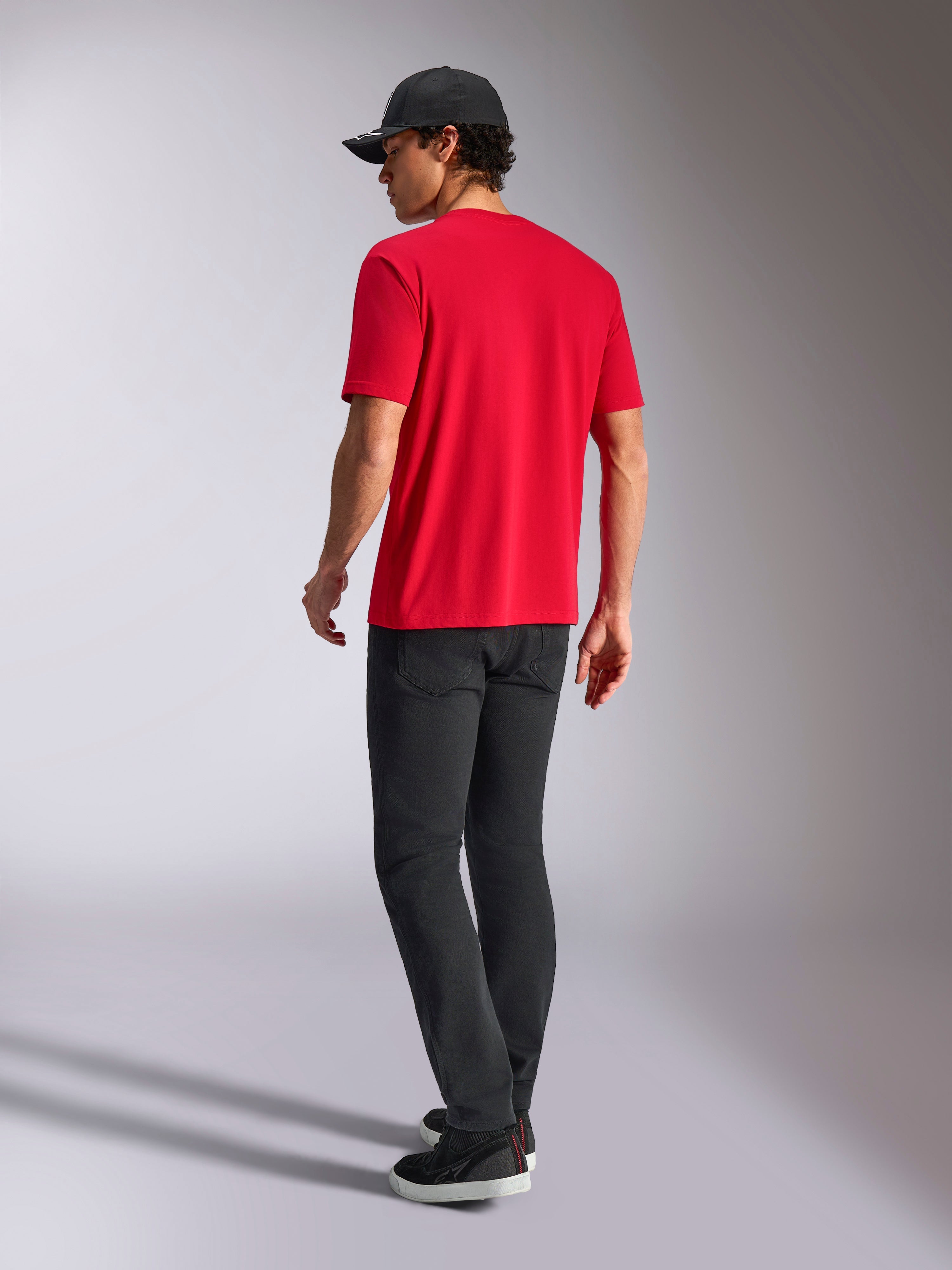 Alpinestars Noka CSF Tee, T-shirt a maniche corte, rosso, vista posteriore, abbinata a pantaloni neri e un cappellino da baseball nero, streetwear casual ispirato al motorsport