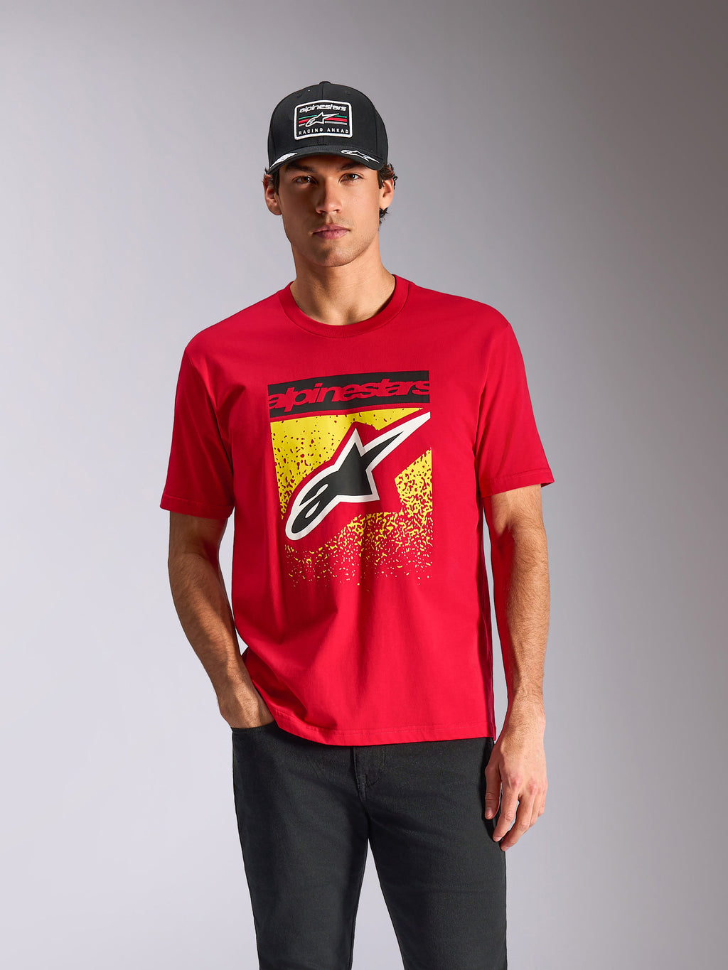 Alpinestars Noka CSF Tee, maglietta a maniche corte, rosso, logo Astars frontale con gradazione MX gialla, indossata da un modello con cappellino Alpinestars nero, streetwear casual motorsport