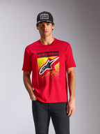 Alpinestars Noka CSF Tee, maglietta a maniche corte, rosso, logo Astars frontale con gradazione MX gialla, indossata da un modello con cappellino Alpinestars nero, streetwear casual motorsport
