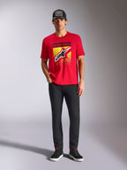 Alpinestars Noka CSF Tee, t-shirt a maniche corte, rossa, con un grande logo Astars frontale con gradazione MX gialla e nera, indossata con pantaloni neri e un cappellino nero, streetwear casual motorsport