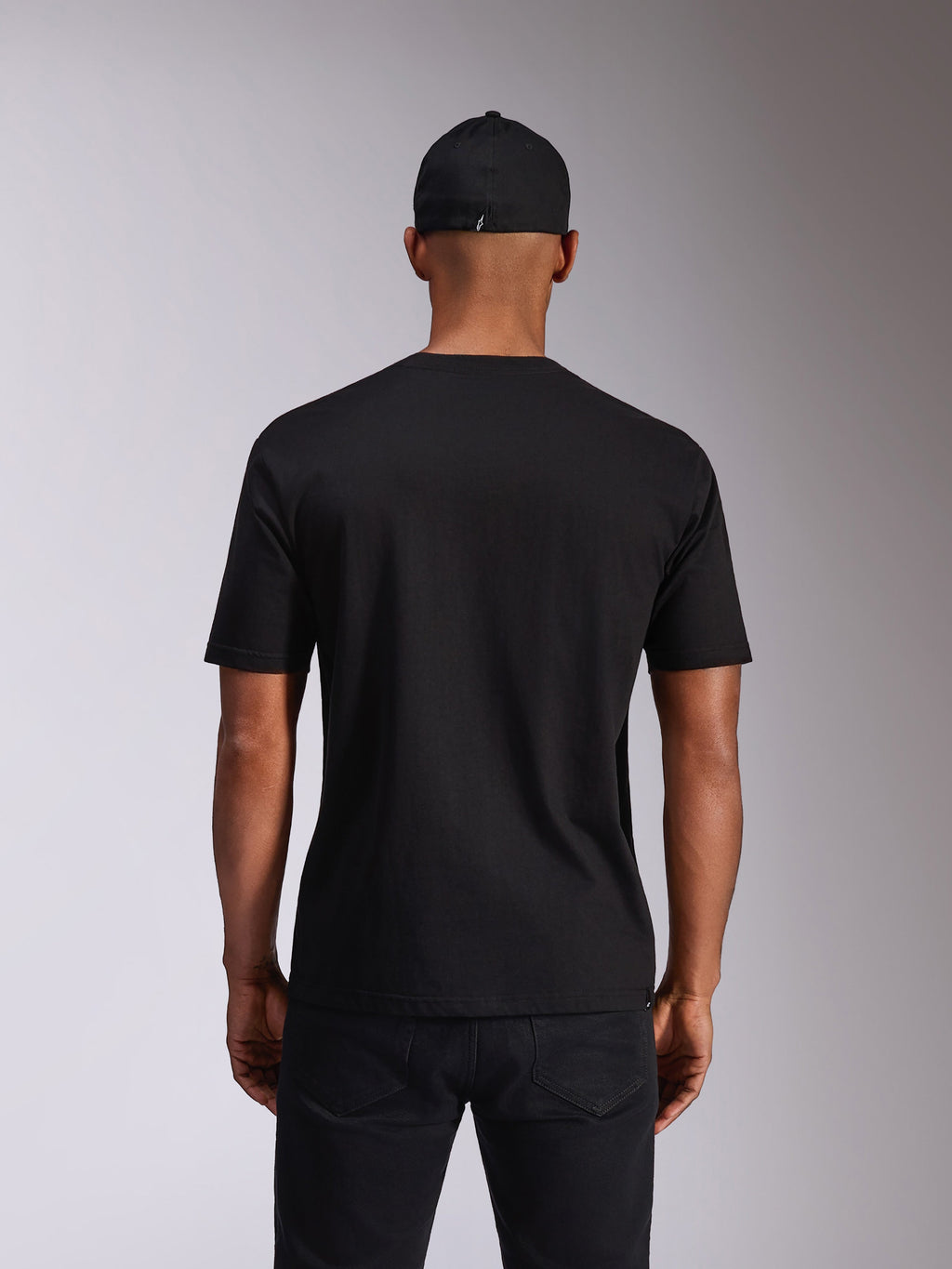 Alpinestars Ellipsoid CSF Tee, maglietta a maniche corte, nero, vista posteriore sul modello, indossata con cappellino nero e pantaloni scuri, streetwear casual ispirato al motorsport