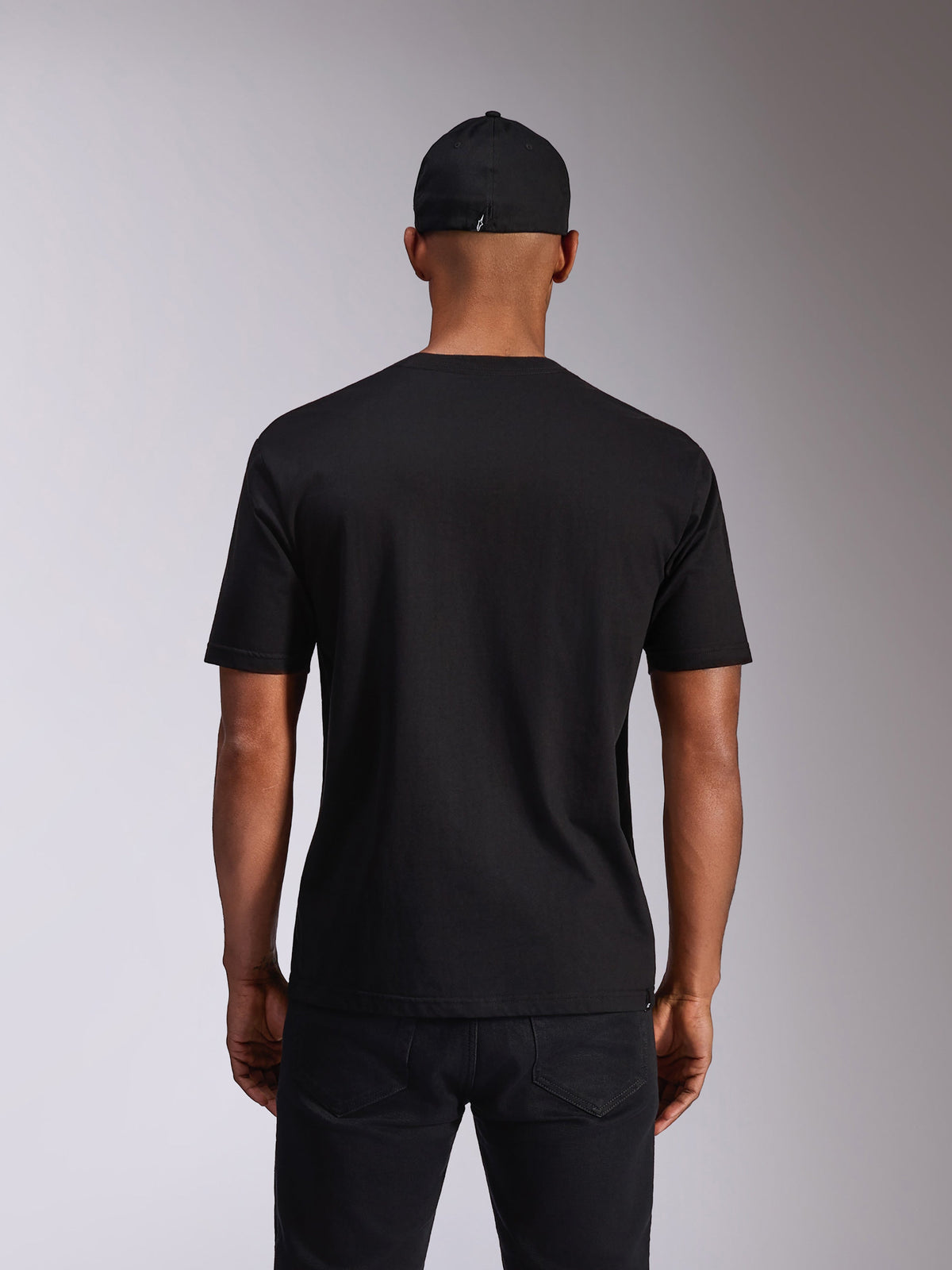 Alpinestars Ellipsoid CSF Tee, maglietta a maniche corte, nero, vista posteriore sul modello, indossata con cappellino nero e pantaloni scuri, streetwear casual ispirato al motorsport