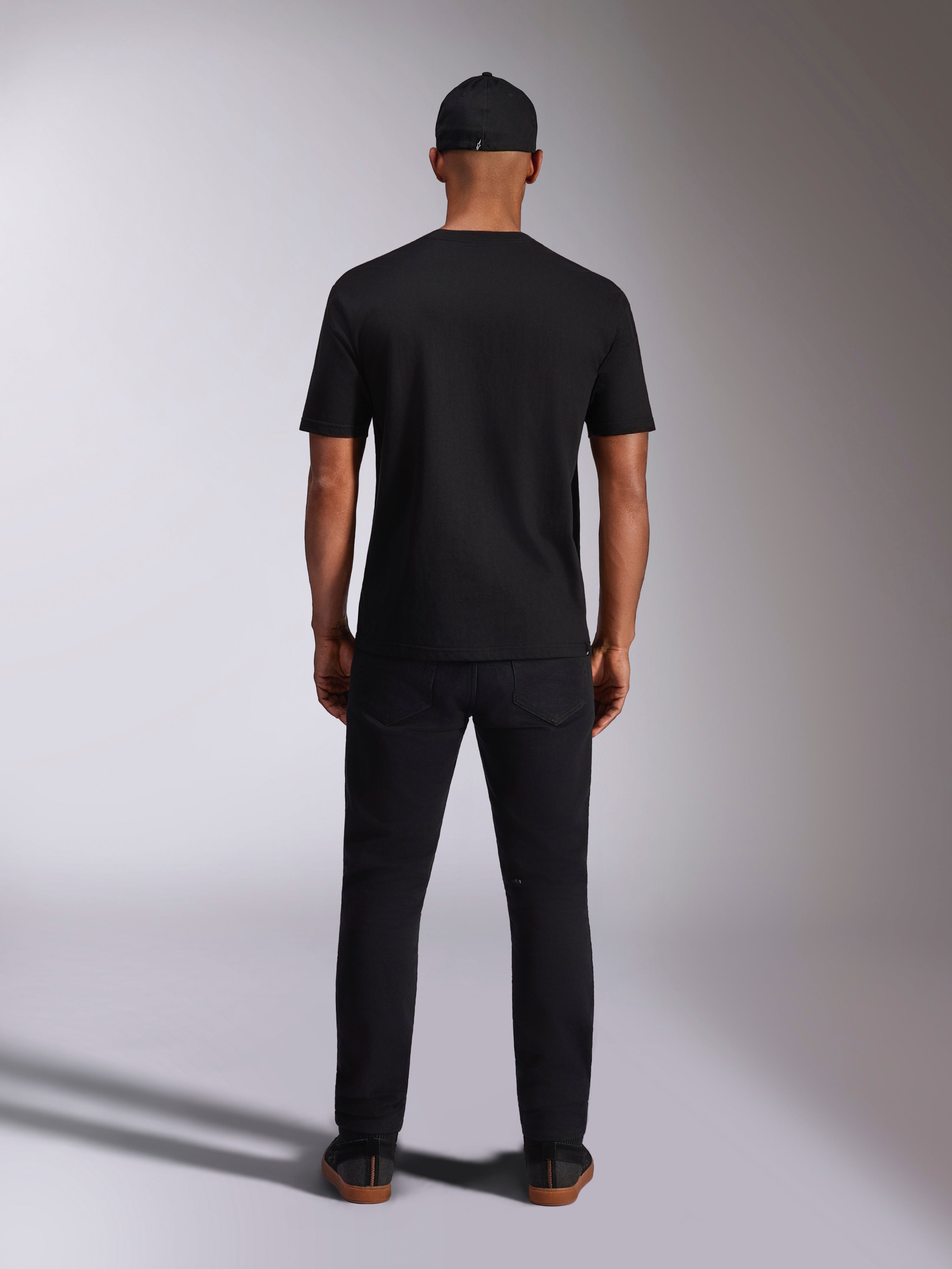 Alpinestars Ellipsoid CSF Tee, maglietta a maniche corte, nero, vista posteriore indossata da un modello con cappellino e pantaloni neri, streetwear casual ispirato al motorsport