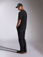 Alpinestars Ellipsoid CSF Tee, maglietta a maniche corte, nera, vista posteriore su modello con pantaloni neri e cappellino Alpinestars nero, outfit casual in stile motorsport