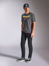 Alpinestars Ellipsoid CSF Tee, t-shirt a maniche corte, grigio antracite, con scritta Astars curva con gradiente di colore e logo bianco, indossata da un modello con pantaloni neri e cappellino, streetwear casual motorsport