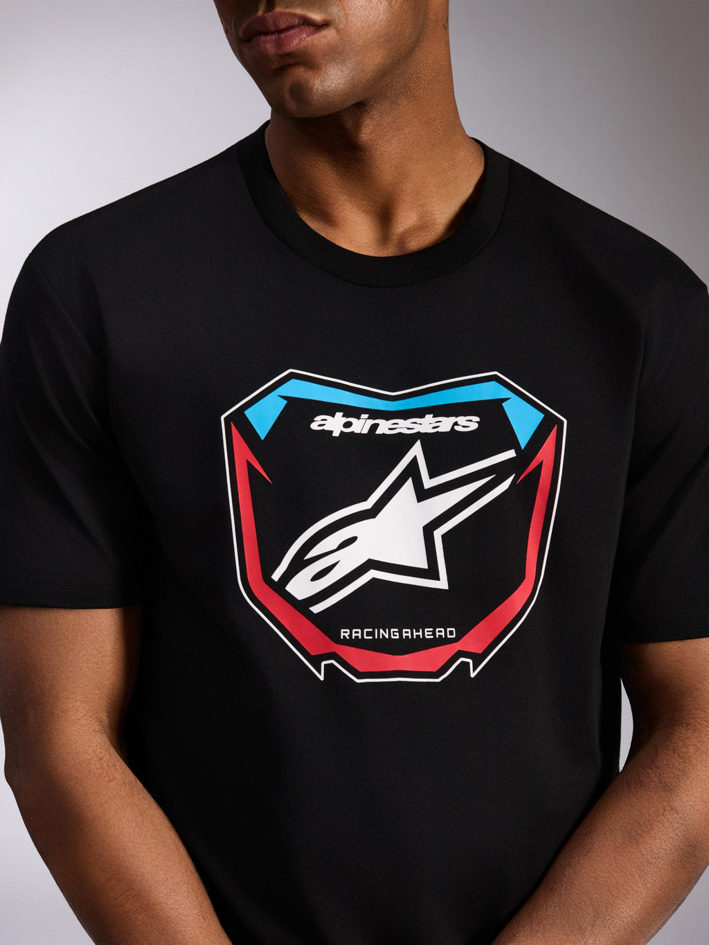 Alpinestars Plate CSF Tee, t-shirt a maniche corte, nera, grafica frontale con tabella da motocross, logo Astars bianco, dettagli rossi e blu e scritta 'RACING AHEAD', streetwear casual ispirato al motorsport