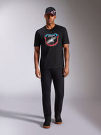 Alpinestars Plate CSF Tee, maglietta a maniche corte, nero, grafica frontale con placca MX, logo Astars bianco e accenti blu e rossi, indossata da un modello con cappellino e pantaloni neri coordinati, abbigliamento sportivo casual motorsport