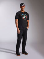 Alpinestars Plate CSF Tee, t-shirt a maniche corte, nero, grafica frontale colorata stile tabella MX con logo a stella, indossata da un modello con cappellino e pantaloni neri, streetwear casual ispirato al motorsport
