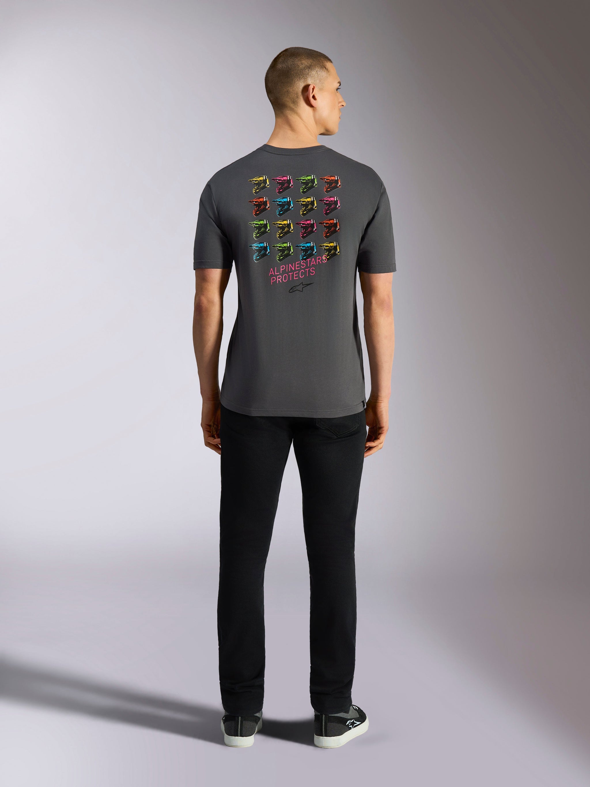 Alpinestars Pop Helmet CSF Tee, maglietta a maniche corte, grigio antracite, con griglia di grafiche multicolore del casco M10 sul retro e scritta 'ALPINESTARS PROTECTS', abbigliamento streetwear casual da motorsport