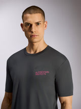 Alpinestars Pop Helmet CSF Tee, T-shirt a maniche corte, grigio antracite, indossata da un modello, con scritta rosa 'ALPINESTARS PROTECTS' e logo Astars sul petto, streetwear casual ispirato al motorsport