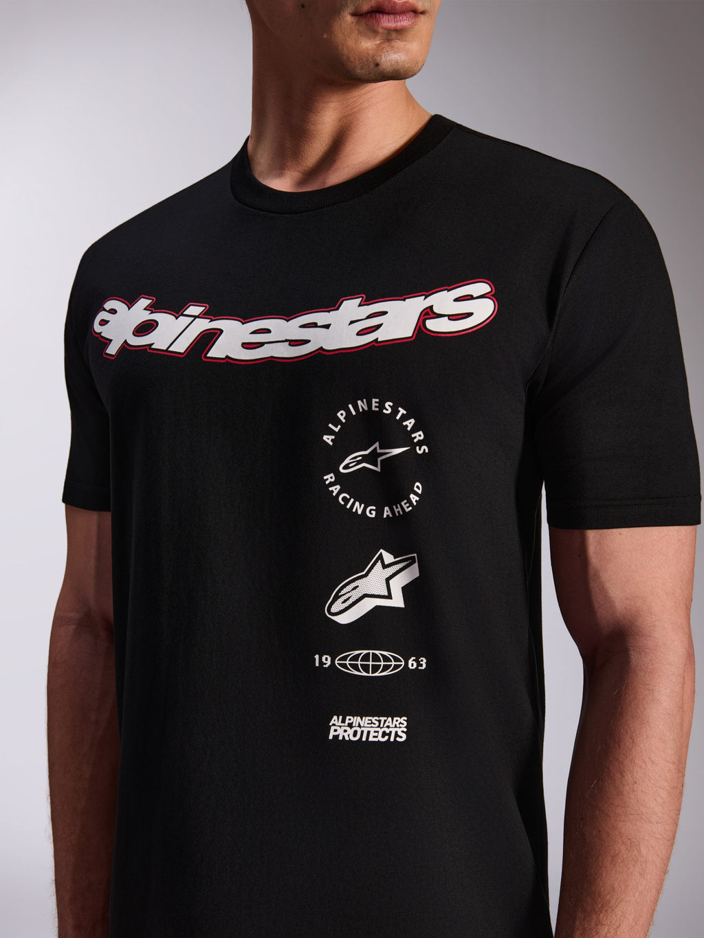Alpinestars Abus CSF Tee, t-shirt a maniche corte, nera, grande logo bianco sul petto con profilo rosso, loghi grafici verticali multipli impilati, abbigliamento casual motorsport streetwear