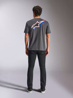 Alpinestars Angler CSF Tee, maglietta a maniche corte, carbone, grande logo Astars multicolore sul retro con accenti rossi e blu, vista posteriore su modello, streetwear casual ispirato al motorsport