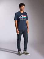Alpinestars Trifecta CSF Tee, t-shirt a maniche corte, blu navy, con logo Astars a strisce tricolore e testo Racing Ahead, indossata da un modello con jeans scuri e sneakers, streetwear casual ispirato al motorsport