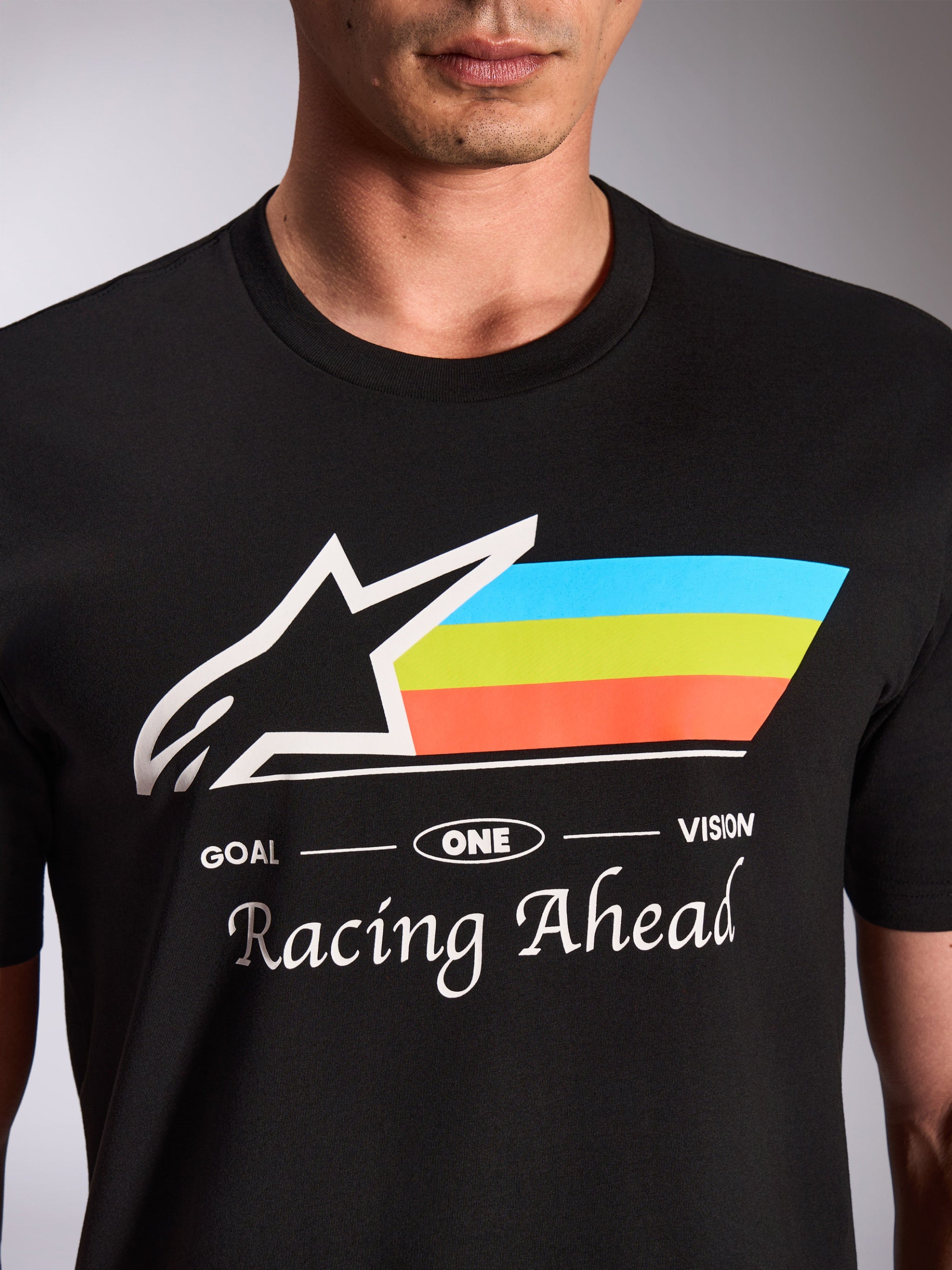 Alpinestars Trifecta CSF Tee, maglietta a maniche corte, nera, primo piano della grafica frontale con logo Astars bianco e strisce tricolore blu, verde e arancione, scritta 'Racing Ahead', streetwear casual motorsport
