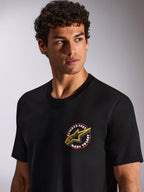 Alpinestars Aorbit CSF Tee, t-shirt a maniche corte, nero, grafica circolare sul petto Always Fast Made to Last con logo Astars giallo, indossata da un modello, streetwear casual motorsport