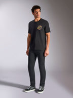 Alpinestars Aorbit CSF Tee, t-shirt a maniche corte, nero, con grafica circolare Always Fast Made to Last sul petto, indossata da un modello con pantaloni scuri slim e sneakers, streetwear casual motorsport