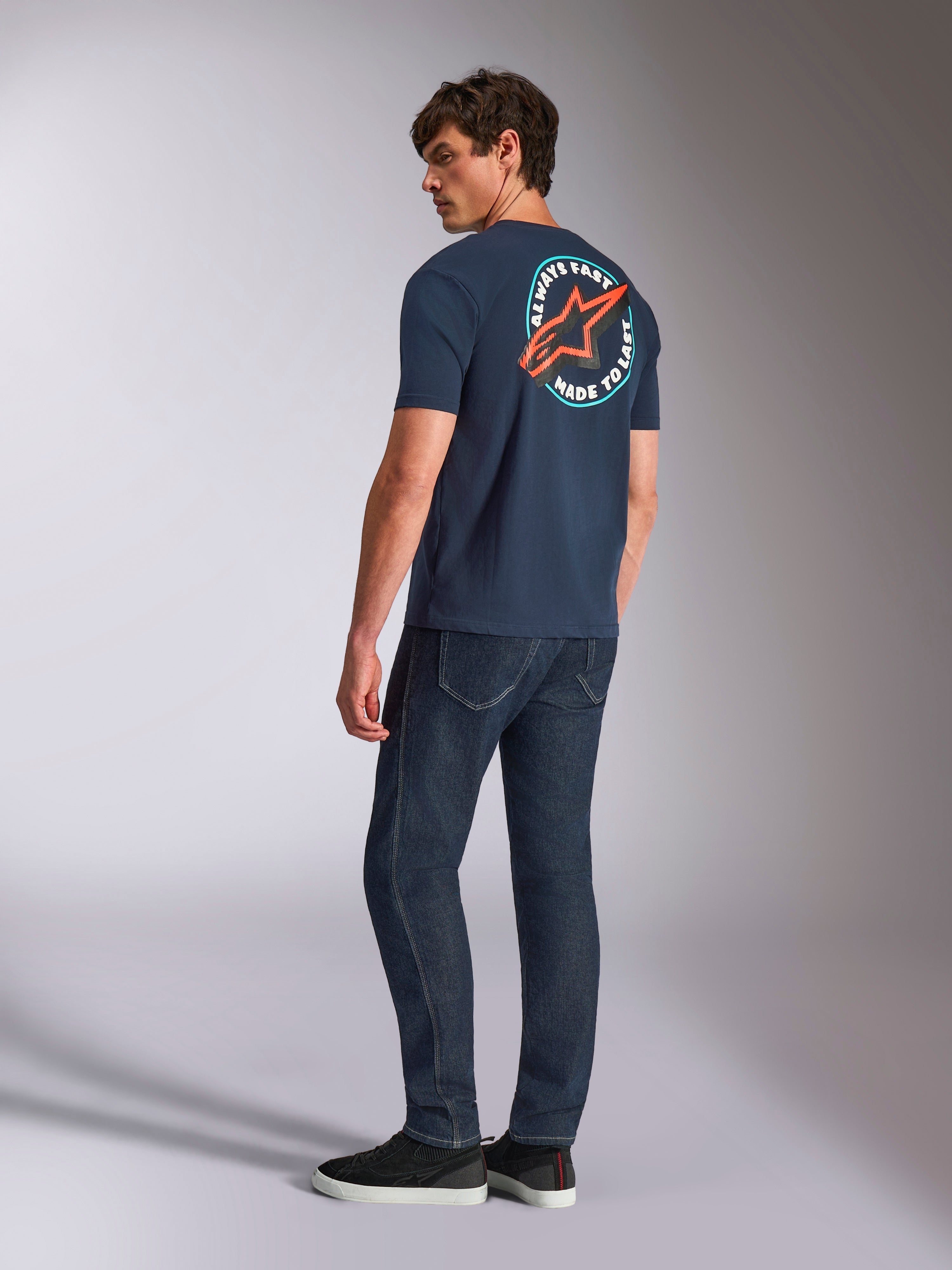 Alpinestars Aorbit CSF Tee, t-shirt a maniche corte, blu navy, vista posteriore su modello con un grande logo Astars circolare e grafica 'Always Fast Made to Last', streetwear casual ispirato al motorsport