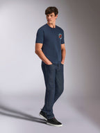 Alpinestars Aorbit CSF Tee, t-shirt a maniche corte, blu navy, con logo Astars circolare arancione e bianco e grafica Always Fast Made to Last, indossata da un uomo con jeans in denim scuro e sneakers nere, streetwear casual ispirato al motorsport