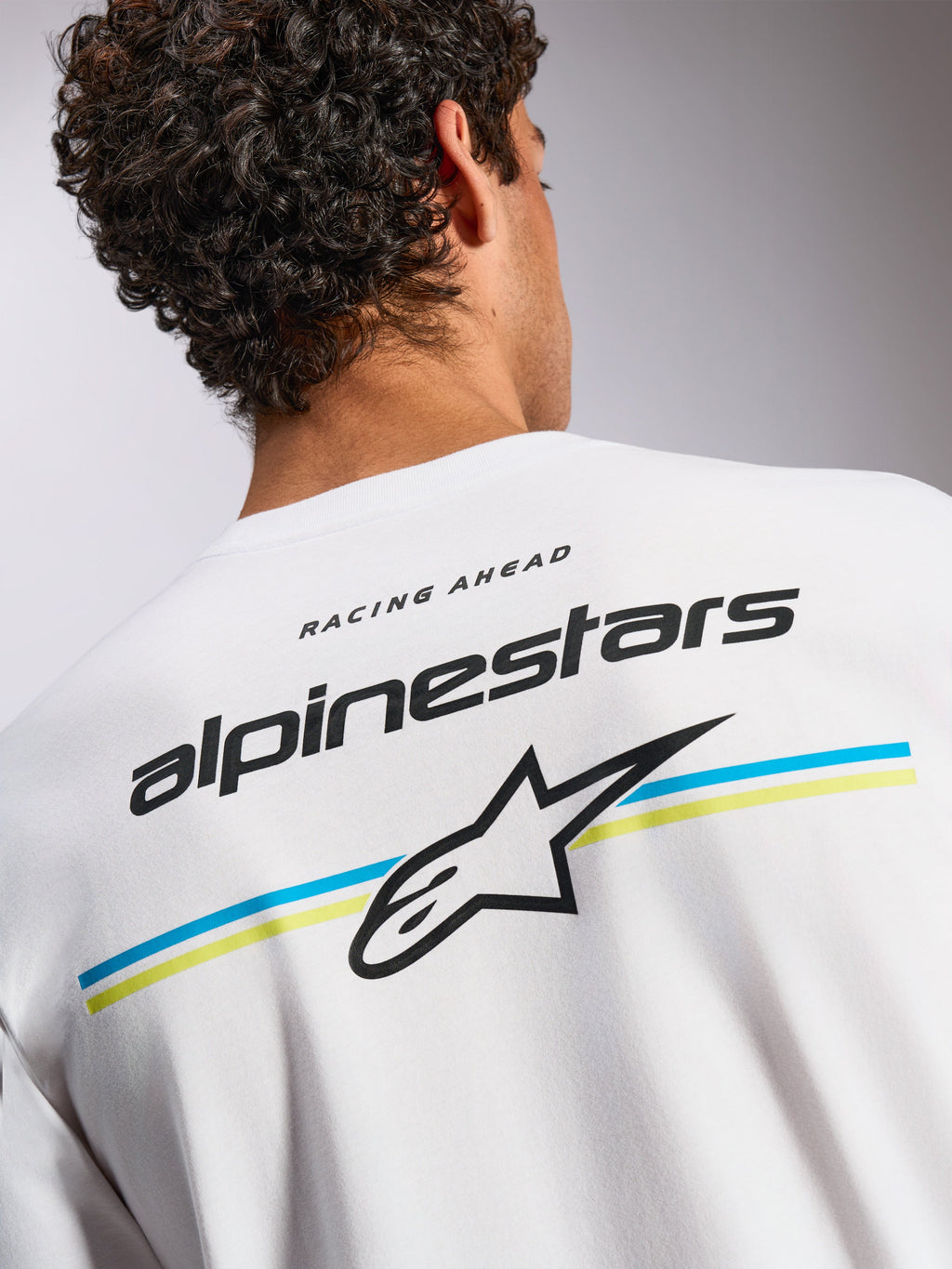 Alpinestars Lanes CSF Tee, t-shirt a maniche corte, bianca, grafica posteriore con scritta Alpinestars e logo Astars su strisce blu e gialle, streetwear casual ispirato al motorsport
