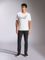 Alpinestars Lanes CSF Tee, t-shirt a maniche corte, bianca, grafica con logo a strisce blu e gialle, indossata da un modello con pantaloni neri e sneakers, streetwear casual ispirato al motorsport