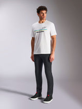 Alpinestars Lanes CSF Tee, White Short Sleeve T-Shirt, worn by model with black slim-fit pants and black high-top sneakers, featuring blue and yellow horizontal stripes with Alpinestars branding on the chest, casual motorsport-inspired streetwear