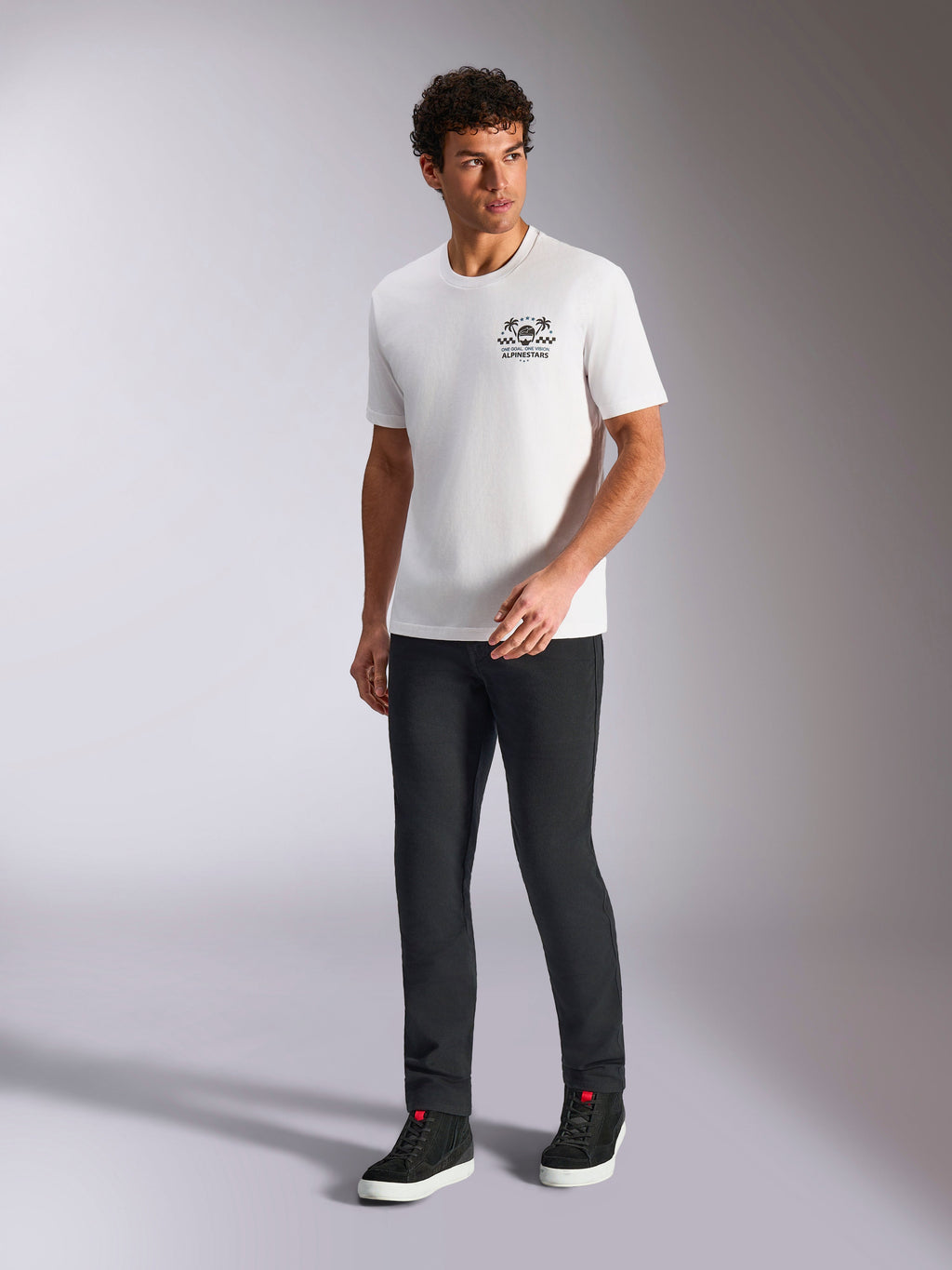 Alpinestars Order CSF Tee, t-shirt a maniche corte, bianca, logo con casco e palme, indossata con pantaloni neri e sneakers alte, streetwear casual motorsport