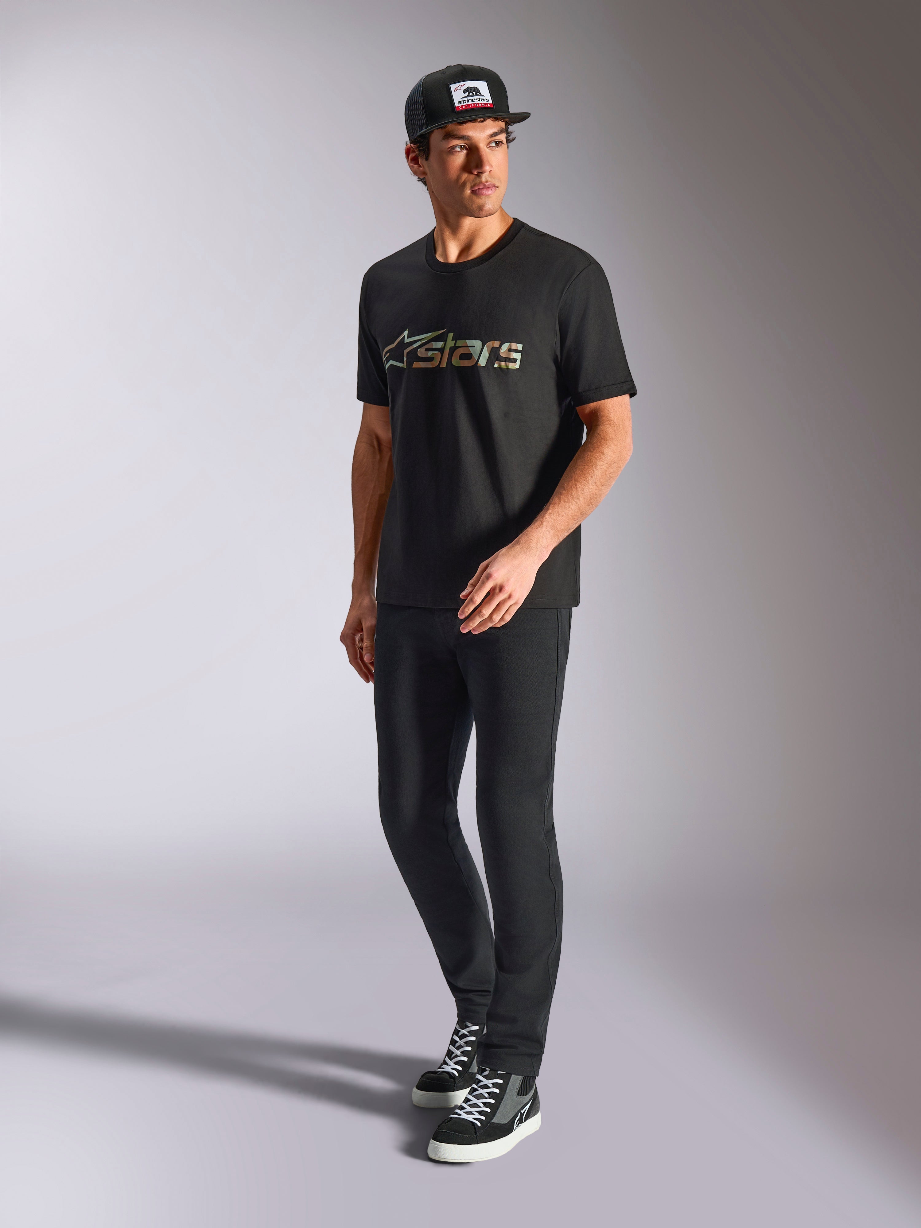 Alpinestars Verdure Camo CSF Tee, t-shirt a maniche corte, nero, con logo Astars con riempimento camo sul petto, indossata da un modello con cappellino e pantaloni neri, streetwear casual motorsport