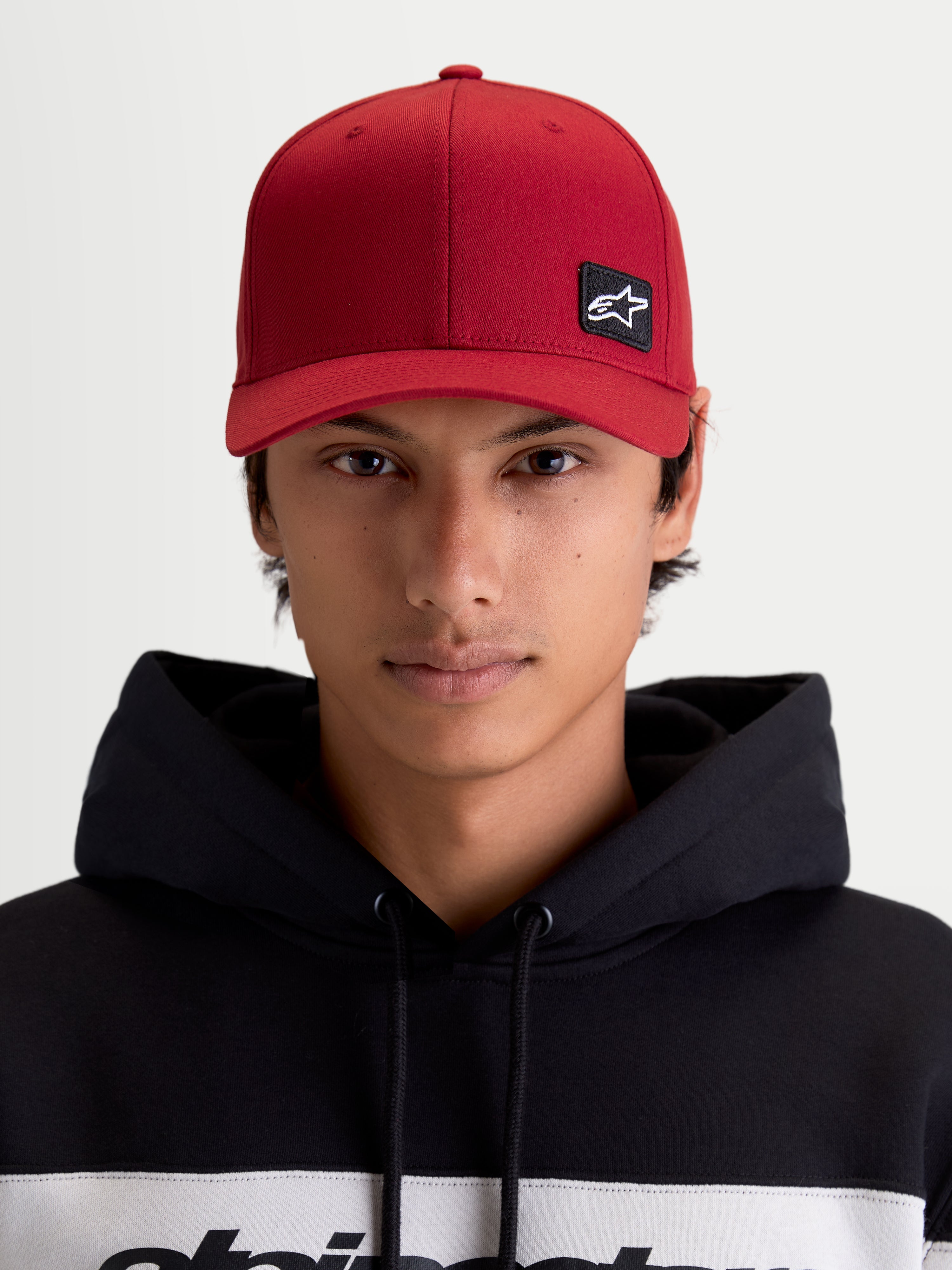 Alpinestars Cappello Pivot, cappello sportswear unisex, rosso scuro, vista frontale su modello con toppa logo Astars ricamata, visiera curva, corona strutturata e costruzione in twill resistente