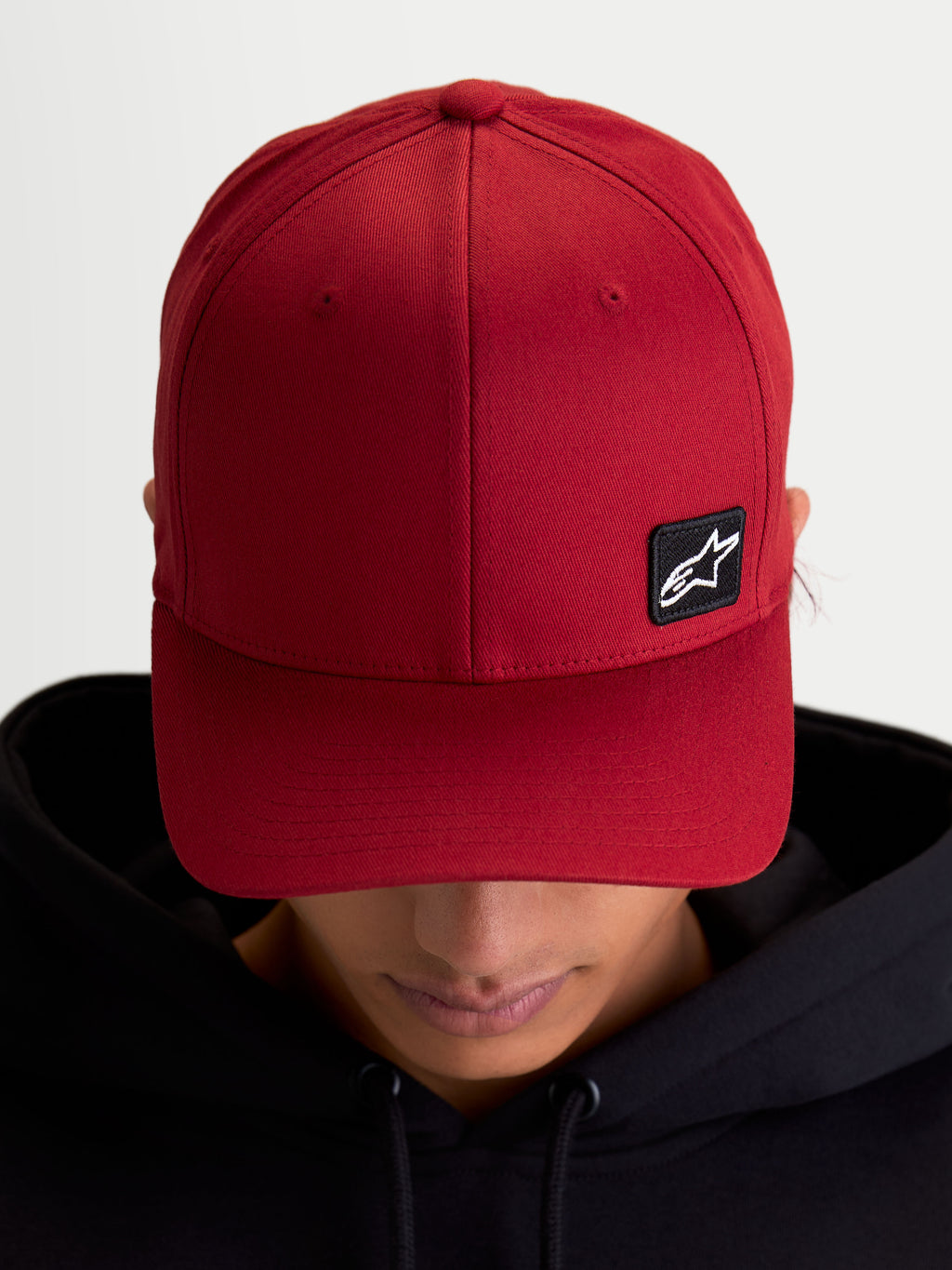 Alpinestars Cappello Pivot, cappello sportswear con visiera curva e corona strutturata, rosso scuro, unisex, piccola toppa nera con logo Astars ricamata su tessuto twill, vista su modello