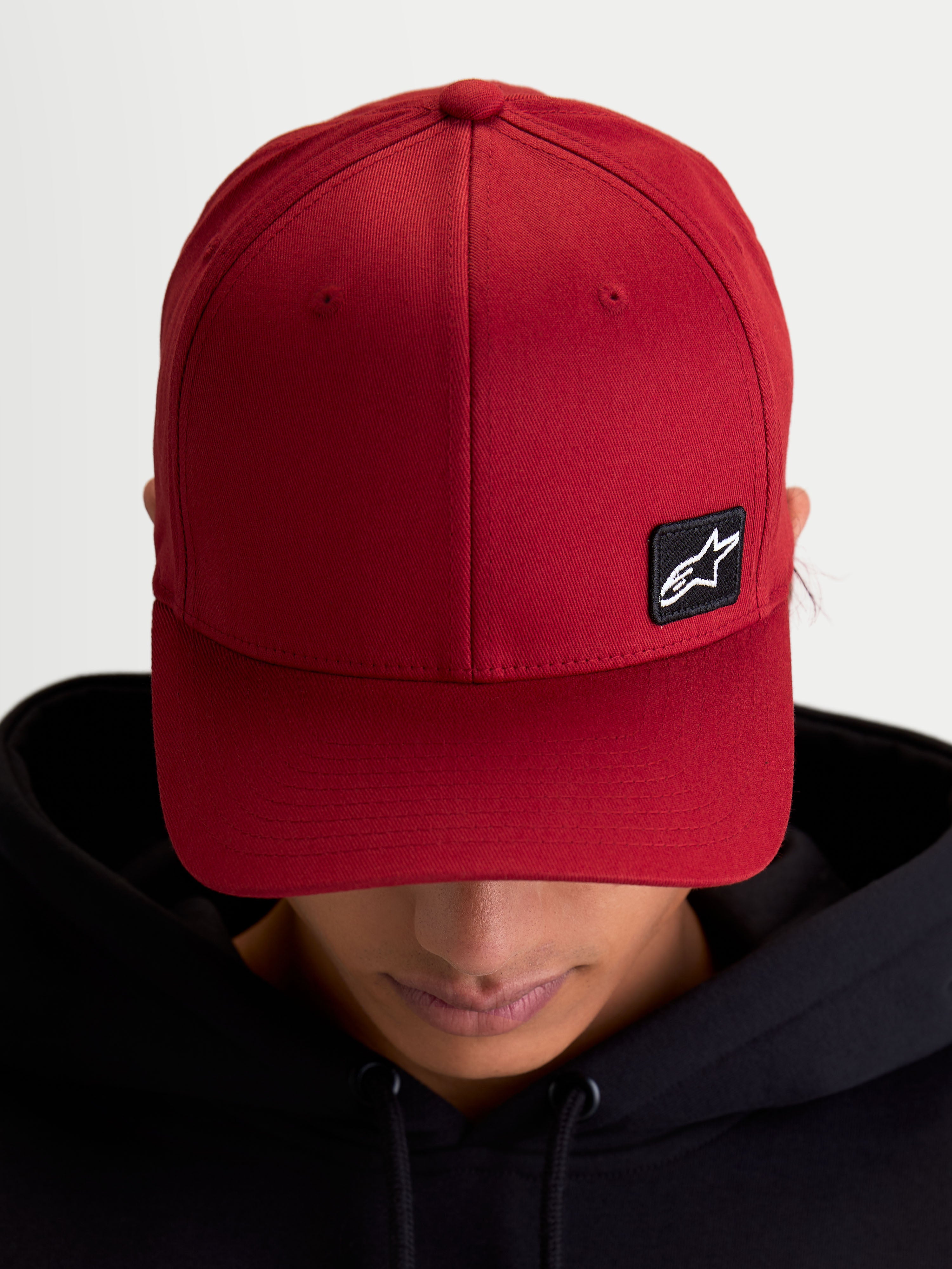 Alpinestars Cappello Pivot, cappello sportswear con visiera curva e corona strutturata, rosso scuro, unisex, piccola toppa nera con logo Astars ricamata su tessuto twill, vista su modello