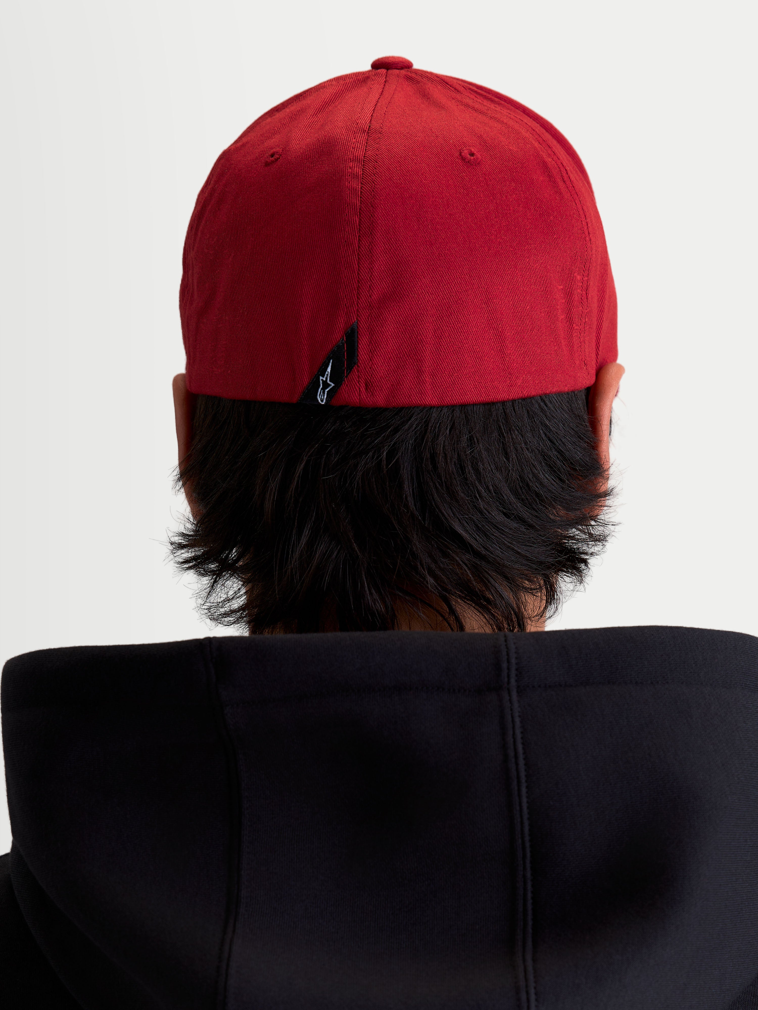 Alpinestars Cappello Pivot, cappello sportswear rosso, vista posteriore su modello con retro flessibile e piccola etichetta nera con logo Astars sul retro