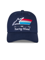 Cappello Alpinestars Trifecta Snapback, cappellino blu navy con visiera curva, con logo frontale ricamato con stella bianca e strisce tricolore, scritte bianche 'Racing Ahead' e 'Goal One Vision', corona strutturata, copricapo casual ispirato al motorsport
