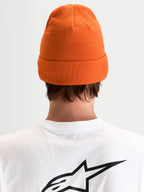 Alpinestars Berretto Augment Cuff, berretto in maglia arancione con design risvoltato e silhouette a vestibilità profonda, vista posteriore di un modello che indossa una maglietta bianca con logo Astar nero