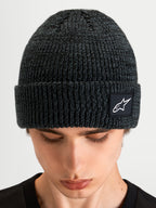Alpinestars Berretto Unload Rib Cuff, berretto invernale in maglia sportswear, grigio scuro melange, con risvolto a coste e patch con logo Alpinestars, indossato da un modello in primo piano