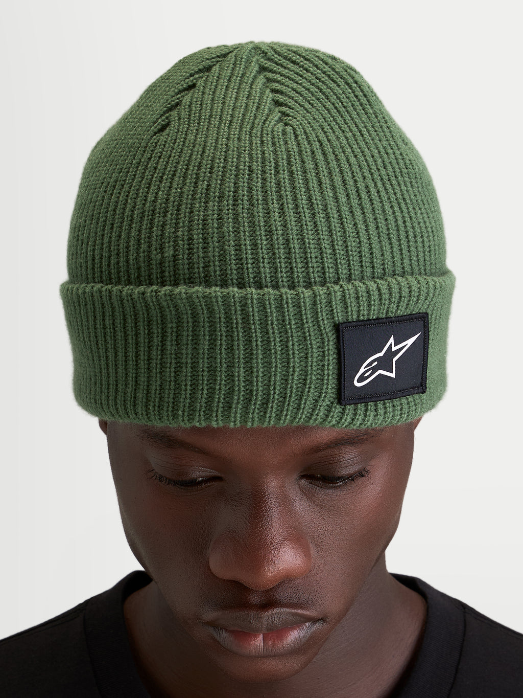 Alpinestars Berretto Unload Rib Cuff, berretto invernale sportswear in maglia, verde pisello, con design a coste e patch tessuta Alpinestars sull'orlo indossato da un modello