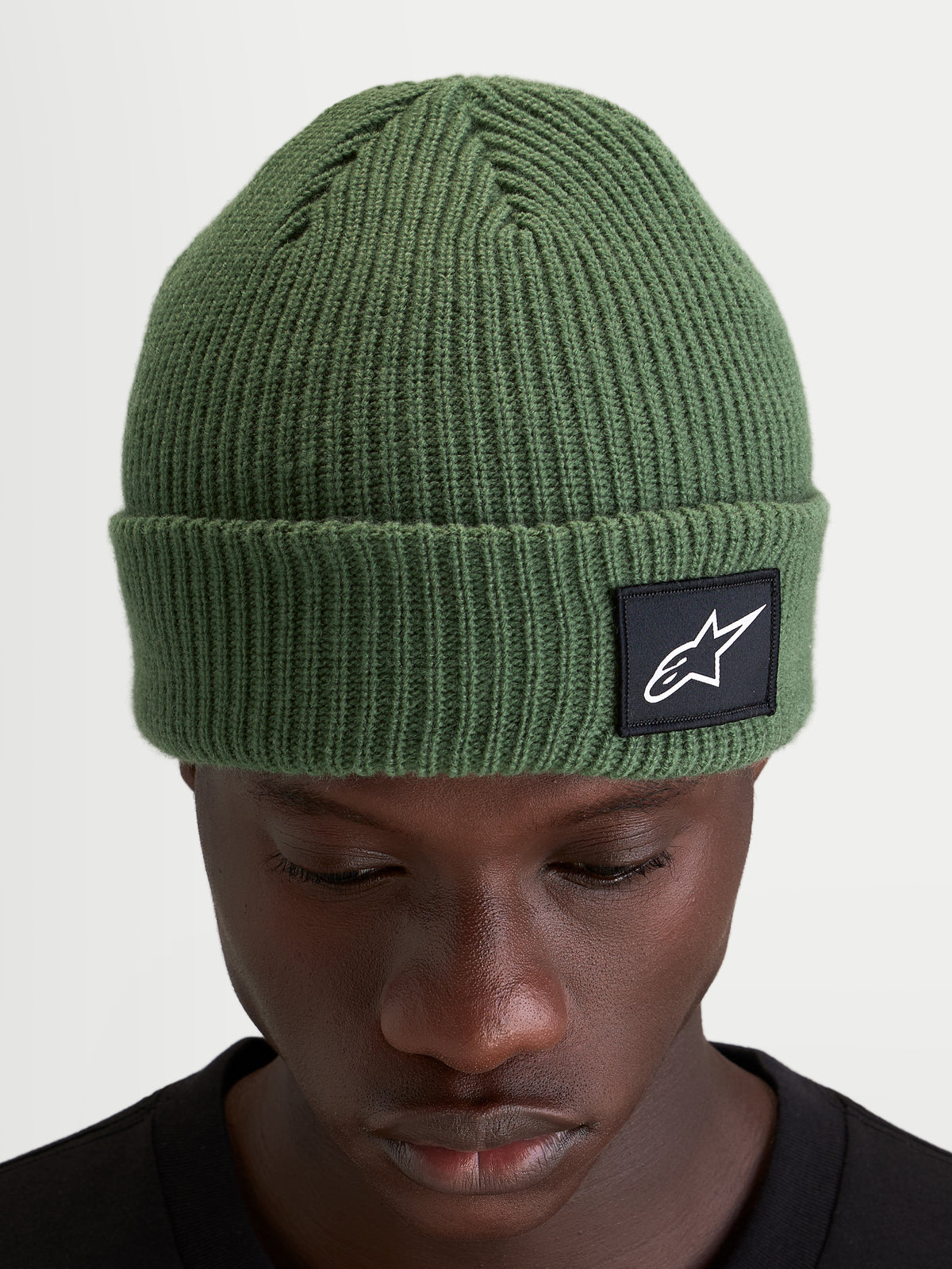 Alpinestars Berretto Unload Rib Cuff, berretto invernale sportswear in maglia, verde pisello, con design a coste e patch tessuta Alpinestars sull'orlo indossato da un modello