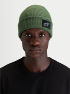 Alpinestars Berretto Unload Rib Cuff, berretto sportswear in maglia verde, indossato da un modello che mostra la silhouette a vestibilità bassa e la patch frontale tessuta SAstars