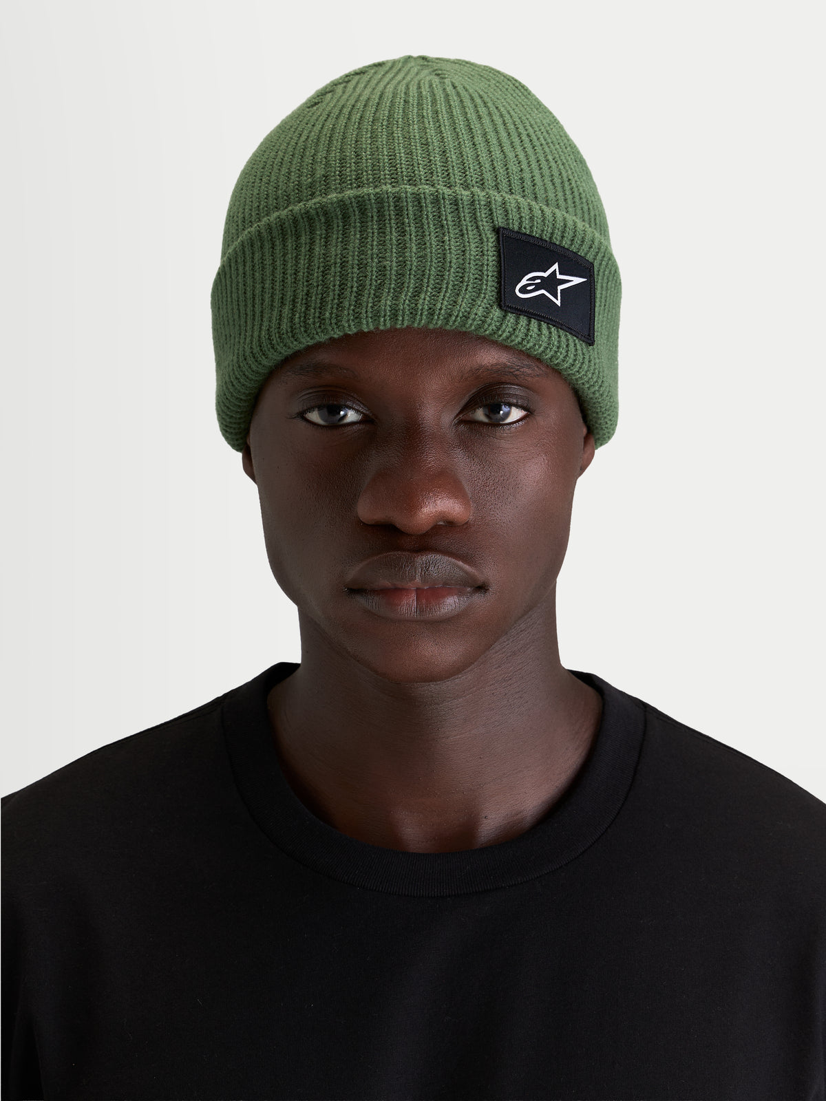 Alpinestars Berretto Unload Rib Cuff, berretto sportswear in maglia verde, indossato da un modello che mostra la silhouette a vestibilità bassa e la patch frontale tessuta SAstars