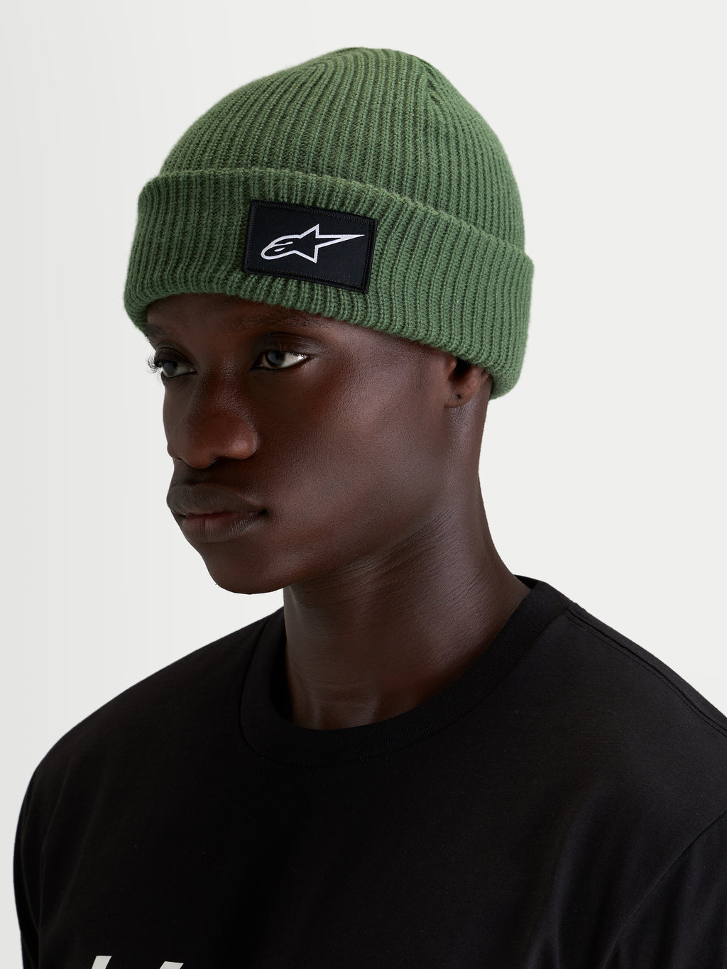 Berretto Alpinestars Unload Rib Cuff, berretto sportswear verde pisello, indossato da un modello, con struttura a maglia a coste e patch frontale SAstars nera e bianca